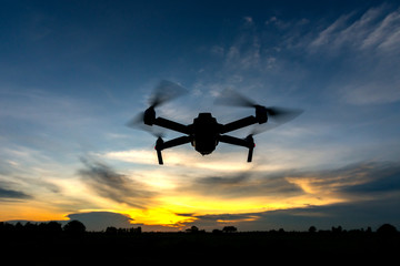drone quadcopter with digital camera flying at sunset.Dark Flying drone and cloud sunrise sky.