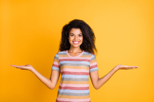 Portrait of her she nice attractive cheerful cheery wavy-haired girl wearing striped tshirt holding on palms two invisible objects isolated on bright vivid shine vibrant yellow color background