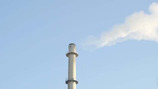 Emissions from a power plant smoke stack with blue sky in the background