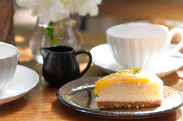 Orange cheese cake serve with tea and coffee set with sun light for tea time.