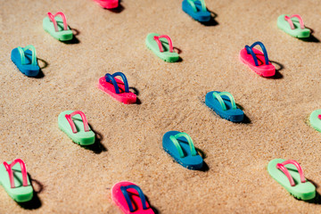 Fototapeta na wymiar Pattern of beach colorful sandals or thongs on a sandy beach.