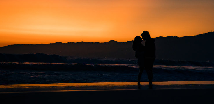 silhouette of couples in love on the beach at sunset