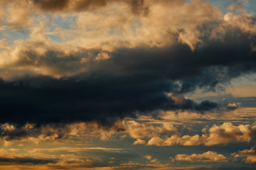 beautiful dramatic sky with dark and bright clouds at sunset, summer landscape, golden sunlight