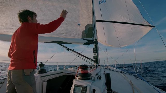 Professional sailor or yachtsman during race. Sailing competition. Man steer and control sail boat in open waters. Stand on boat deck, read sail computer data