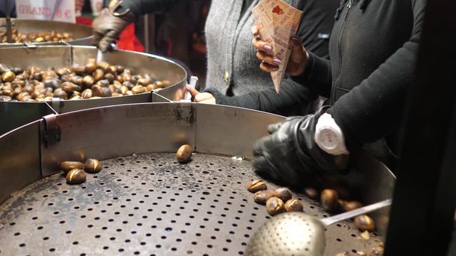 Mains ramassant des marrons chauds pour les mettre dans un cone
