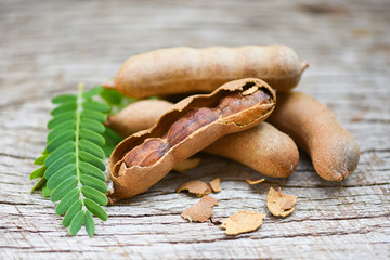Sweet tamarind on wooden background - fresh tamarind fruits and leaves