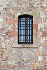 Fototapeta na wymiar Window with Iron Bars Set in Old Stone Wall 