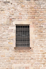 Fototapeta na wymiar Window with Iron Grill set in Rough Stone Wall 