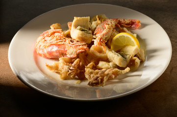 Grilled Calamari (Squid) and shrimps with lemon and parsley on white plate on a plate in restaurant ready to be served