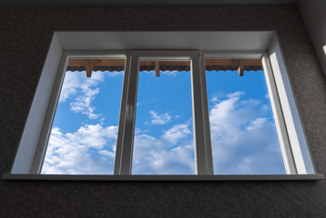 Window overlooking the blue sky with clouds. Focus on the clouds