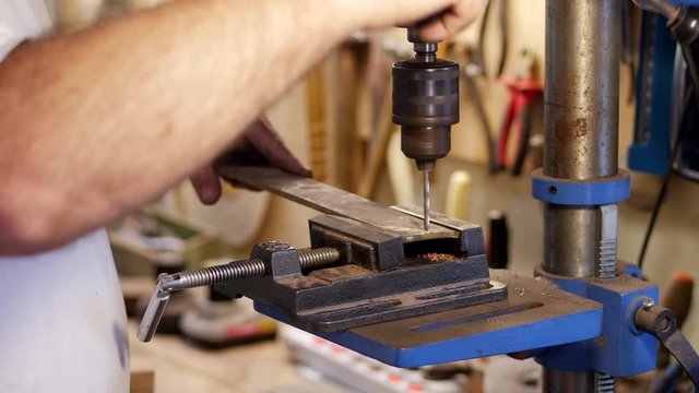The master using a milling machine makes a hole on a piece of metal