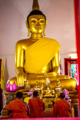 The blurred abstract background of the monks chanting in the chapel, with a large Buddha statue,a...