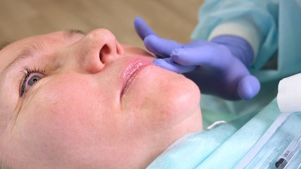 Lip augmentation. Beautician doctor doing a beauty procedure to female lips with a syringe. elderly woman. Lip augmentation.