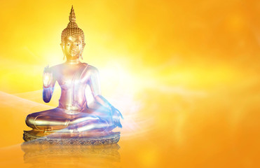 Golden Buddha statue with glittering aura on a golden yellow background for design and a beautiful...
