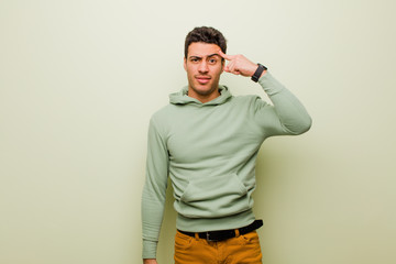 young arabian man feeling confused and puzzled, showing you are insane, crazy or out of your mind...