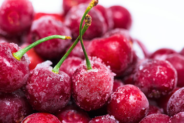 group of frozen cherries on a white background in a white plate. . close up. ice crystals on the fruit. vertical photo of the top view . macro