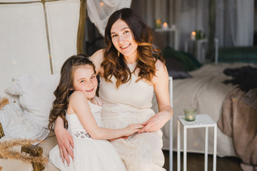 Mother and daughter hugging and playing together. Pretty little girl and beautiful woman. Girls in lace dresses playing in decorated room. Family weekend, beauty day, having fun, love concept.