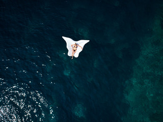 Turquoise ocean water and relaxed swimming woman, aerial drone shot. top down
