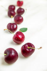Juicy wet red cherries on white marble table, vertical composition