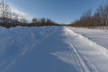 Fototapeta na wymiar The dirt road is covered with ice and snow .Clear blue sky.