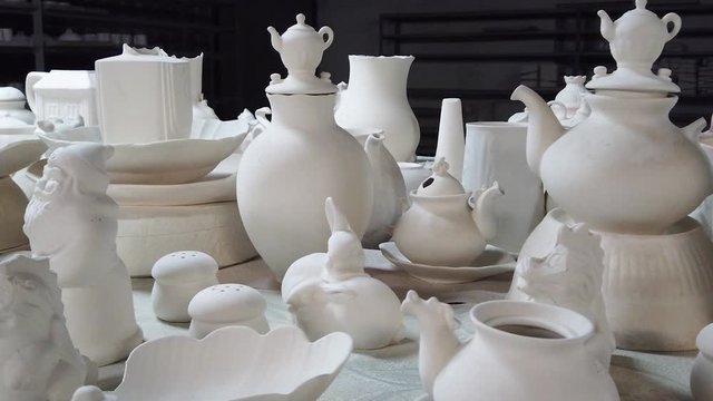 Factory of porcelain and ceramics. Clay blanks of mugs, teapots and jugs are dried on tables and racks.