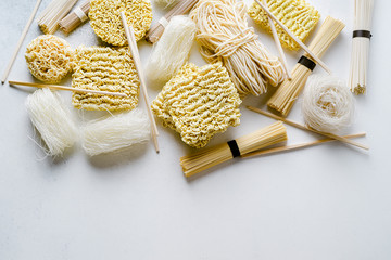 Variety of uncooked asian noodles on light background, banner wit copy space