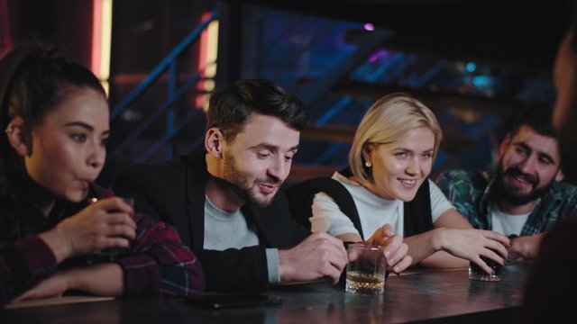 Young charismatic group of friends in a bar celebrating something they start drinking tasting the cocktails and feeling so relaxed and excited. 4k