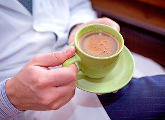 young attractive doctor in a white coat holds a cup of coffee and rests on a coffee break