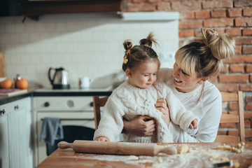 Mother and daughter baking cookies and hugging