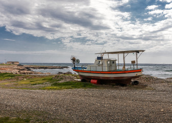 Old and broken wooden metal boat stranding on sea beach on island of Cyprus.