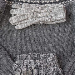 Fototapeta na wymiar Warm female gray knitted gloves, socks on a sweater textured background. Flat lay, top view minimal fashion concept.