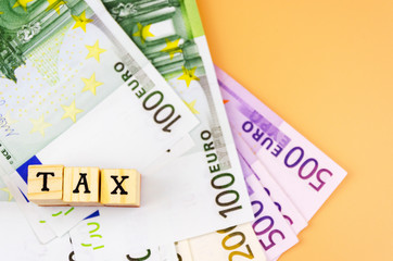 the word tax and the currency of the European Union of different denominations on an orange background 5