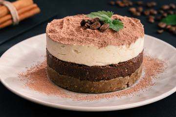 Tiramisu on a beige plate. Coffee with cinnamon. Raw dessert