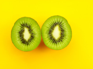 two halves of kiwi on a yellow background.