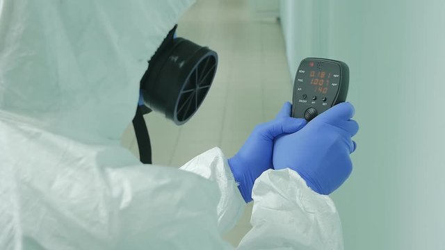 a virologist measures the level of radiation and determines the amount of harmful substances in the room