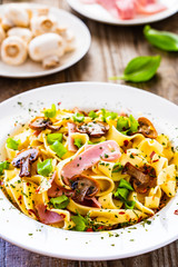Tagliatelle with ham and chmpignon wooden table