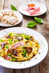 Tagliatelle with ham and chmpignon wooden table