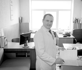 young attractive doctor in a white coat writes the patient’s story in the office of his clinic