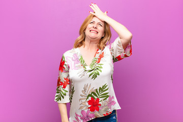 middle age woman raising palm to forehead thinking oops, after making a stupid mistake or...