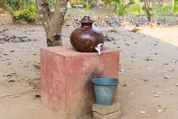 Earthen ware pot hand made and used for holding drinking water with plastic bucket for collecting drips