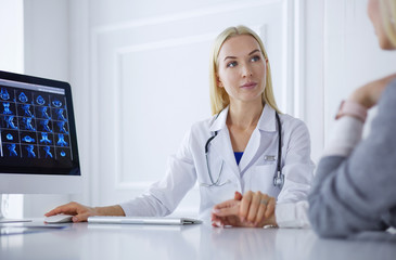 Doctor and patient discussing something while sitting at the table . Medicine and health care concept