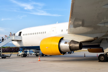 Big modern passenger airplane parked on airfield after arrival on bright sunny summer day. People...