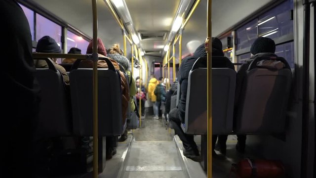 View inside the passenger compartment of the bus. The bus with people goes through the night city. Lights flash past the Windows. View from the back of the bus. Blurred background. 4K.