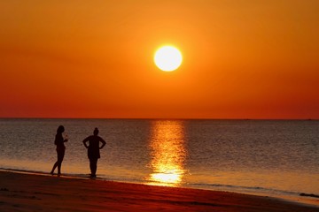 Sunset with orange sky at Nacpan beach with two girls, El Nido, Palawan, Philippines