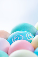 Colorful Easter eggs dyed by colored water isolated on a pale blue background, design concept of Easter holiday activity, close up, copy space.