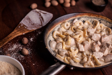 A bowl of pesto tortellini with chicken and sauce
