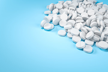 Heap of white round pills at the blue table. Top view with copy space. Pharmaceutical industry and health care concept.