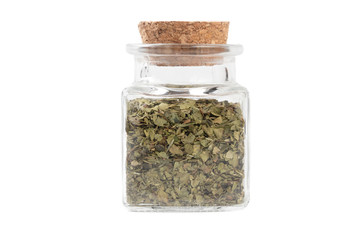 dried lovage herb in a glass jar isolated on white background. spices and food ingredients