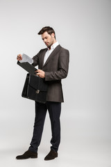 Serious young businessman holding bag and clipboard.