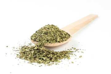 dried lovage herb in wooden spoon isolated on white background. spices and food ingredients. spices and food ingredients
